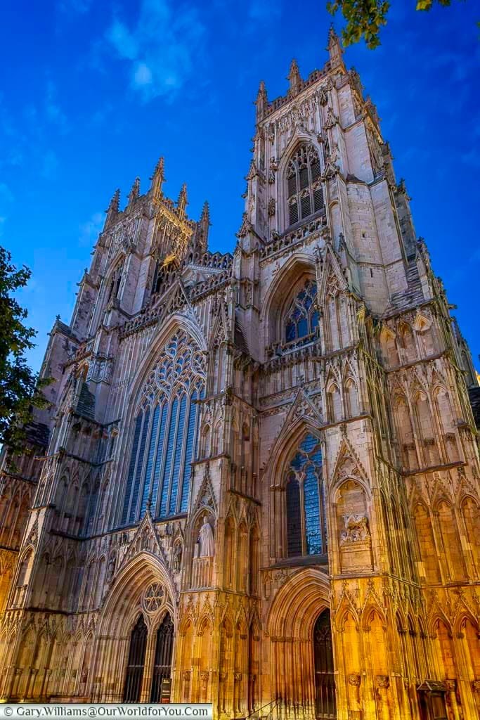 York Minster illuminated at night, its Gothic towers glowing beautifully against the deep blue sky. One of the most iconic views in York, this landmark is a must-see by day and night.