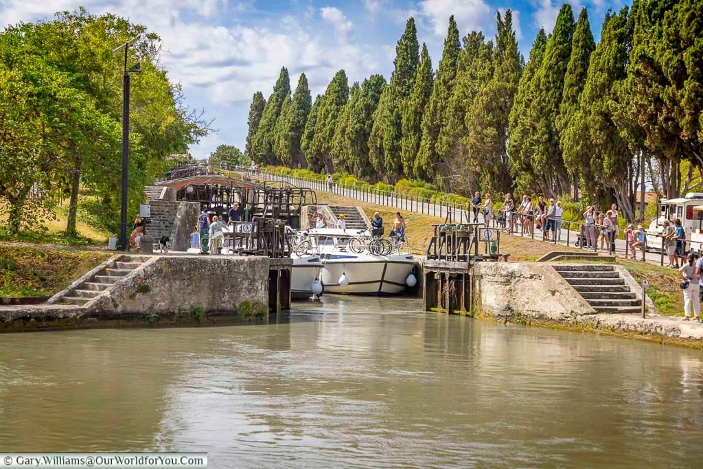 Boats navigating the famous 9 Locks of Fonseranes near Béziers, with tourists watching along the Canal du Midi. A marvel of 17th-century engineering, this historic canal site is a must-see attraction for anyone exploring southern France by road or water.