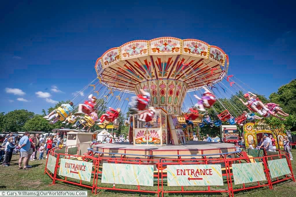 A colourful chair-o-plane ride spins joyfully under a bright blue summer sky at the Kent County Show. This traditional fairground favourite brings delight to families enjoying a classic British day out.