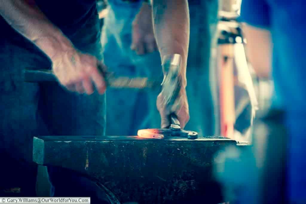 A traditional blacksmith skillfully hammers a glowing horseshoe on an anvil at the Kent County Show. This rural craft demonstration showcases heritage trades still celebrated in the UK countryside.