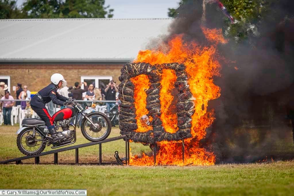 A stunt rider from the British Army prepares to leap through a blazing ring of fire during a thrilling live demonstration at the Kent County Show. This high-octane moment highlights the adrenaline-fueled entertainment often featured at traditional UK rural events.