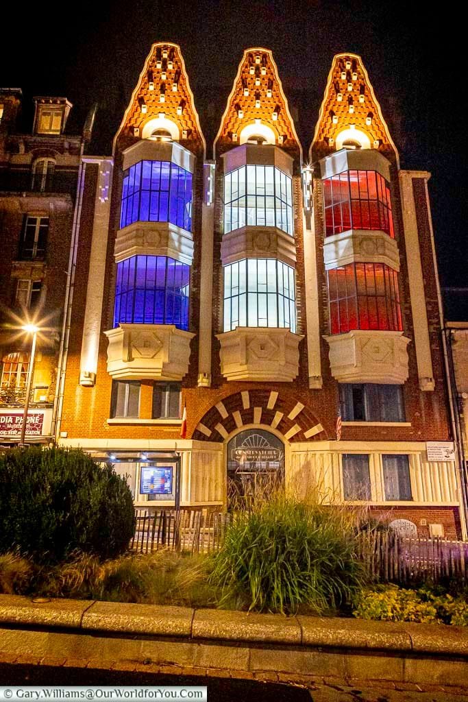 A striking Art Déco building in Saint-Quentin, France, illuminated at night in the colours of the French flag—blue, white, and red. This iconic architecture highlights the city's vibrant urban heritage and patriotic spirit.