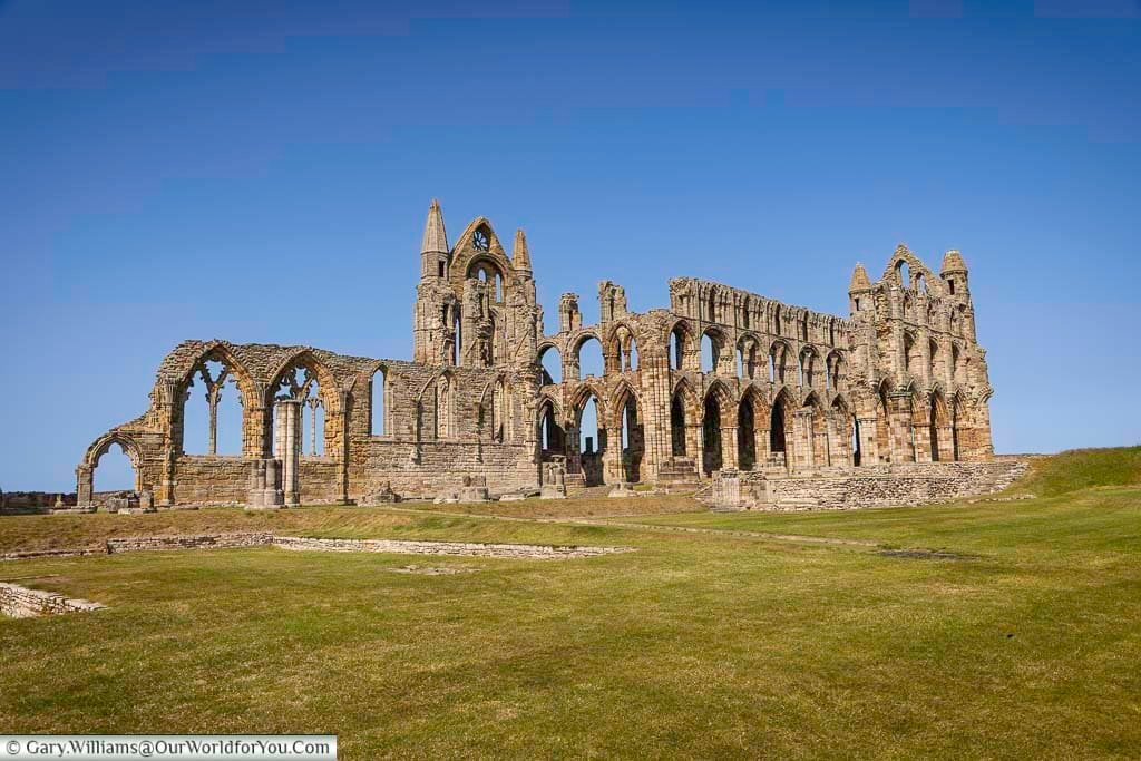 An expansive side view of the hauntingly beautiful Whitby Abbey ruins, with its medieval arches and intricate stonework still commanding attention centuries later. This English Heritage site inspired Bram Stoker’s Dracula.