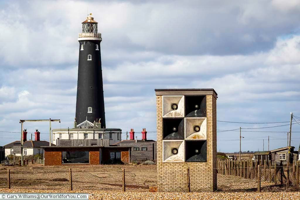 The black Dungeness High Light Tower rises behind a WWII-era foghorn station, creating a unique silhouette on the Kent coast. This image captures Dungeness’s layered history of maritime navigation and communication.