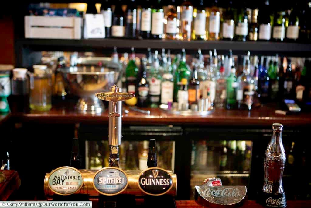 A glimpse into the cosy interior of the Britannia Inn at Dungeness, with its well-stocked bar, nautical decor, and local Kent ales on tap. This popular pub is a perfect stop for visitors exploring the stark beauty of the Dungeness landscape.
