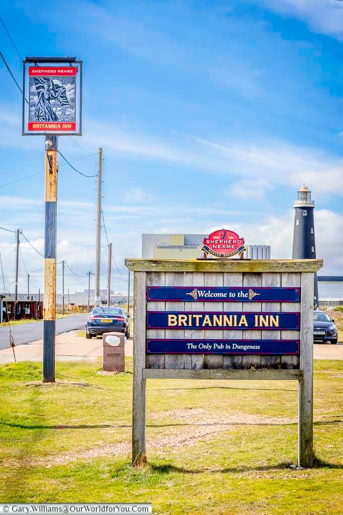 The sign for the Britannia Inn proudly welcomes visitors to the only pub in Dungeness, with the iconic black lighthouse and nuclear power station in the background. A must-visit spot on Kent’s unique shingle headland.