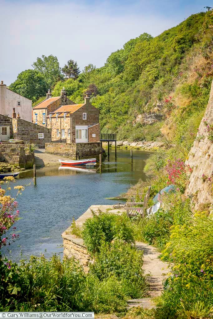 A quiet corner of Staithes Harbour is framed by greenery and stone-built fisherman’s cottages with boats gently moored nearby. This secluded nook offers a peaceful escape along the Yorkshire coast.