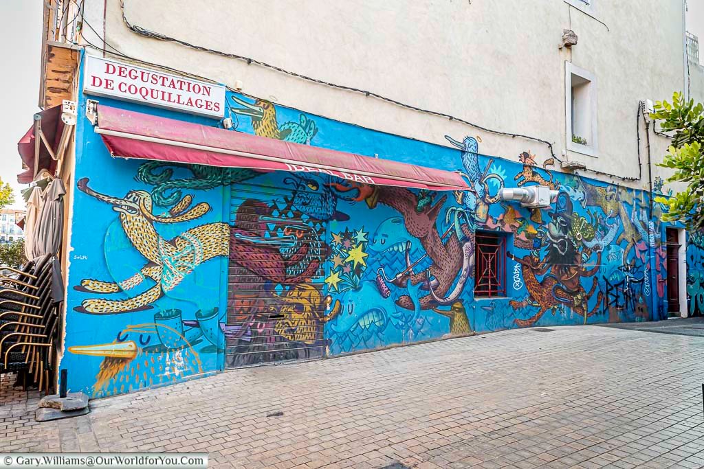 A bold street mural in Sète, France, bursts with fantastical creatures and vibrant colours, transforming an ordinary alley into an urban art gallery. This quirky wall art reflects the town’s creative spirit and eclectic character.
