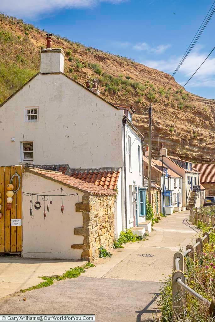 Charming seaside cottages line the narrow path by Cowbar Bank in Staithes, North Yorkshire, with red sandstone cliffs towering above. This peaceful coastal lane offers a nostalgic glimpse into the village’s fishing heritage.