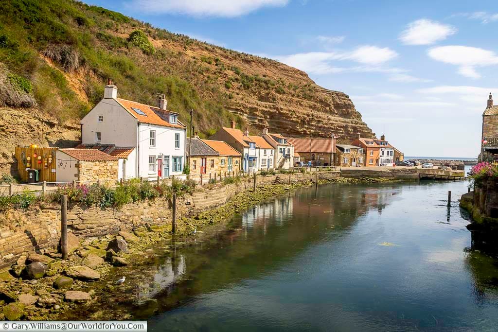 Staithes Beck winds past a row of heritage cottages and a tidal slipway as it flows toward the North Sea. The sandstone cliffs and vibrant facades make this view a coastal photographer’s dream.