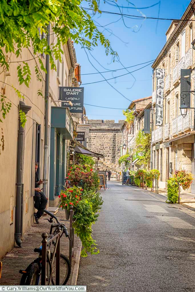 Charming flower-lined lane in Aigues-Mortes, France, leading toward the medieval city walls. Discover hidden gems and historic architecture in this walled Occitanie town.