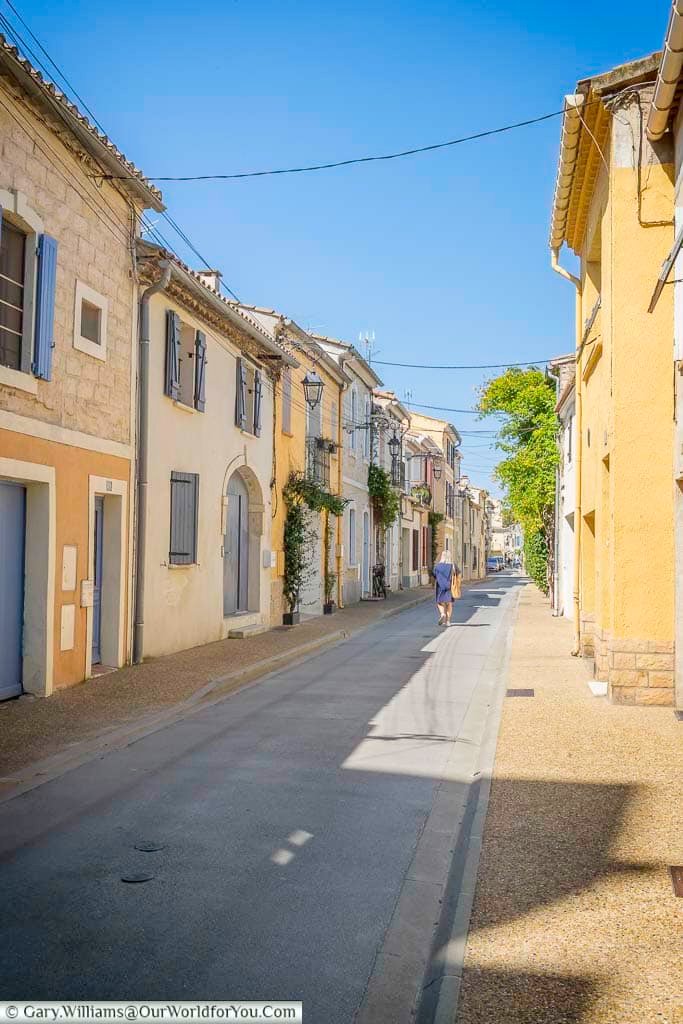 The quiet charm of Rue Roger Salengro features sun-washed facades, colourful shutters, and a lone figure strolling this peaceful residential lane. It’s a hidden gem for visitors seeking the authentic atmosphere of Aigues-Mortes beyond the tourist crowds.