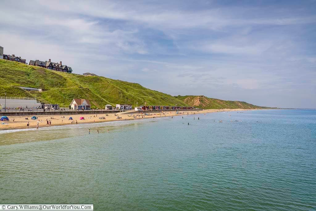 Saltburn’s golden sandy beach curves gently along the dramatic green cliffs of the Yorkshire coastline, offering a picturesque retreat for swimmers and sunbathers. Colourful beach huts dot the promenade, adding to the town’s nostalgic seaside charm.