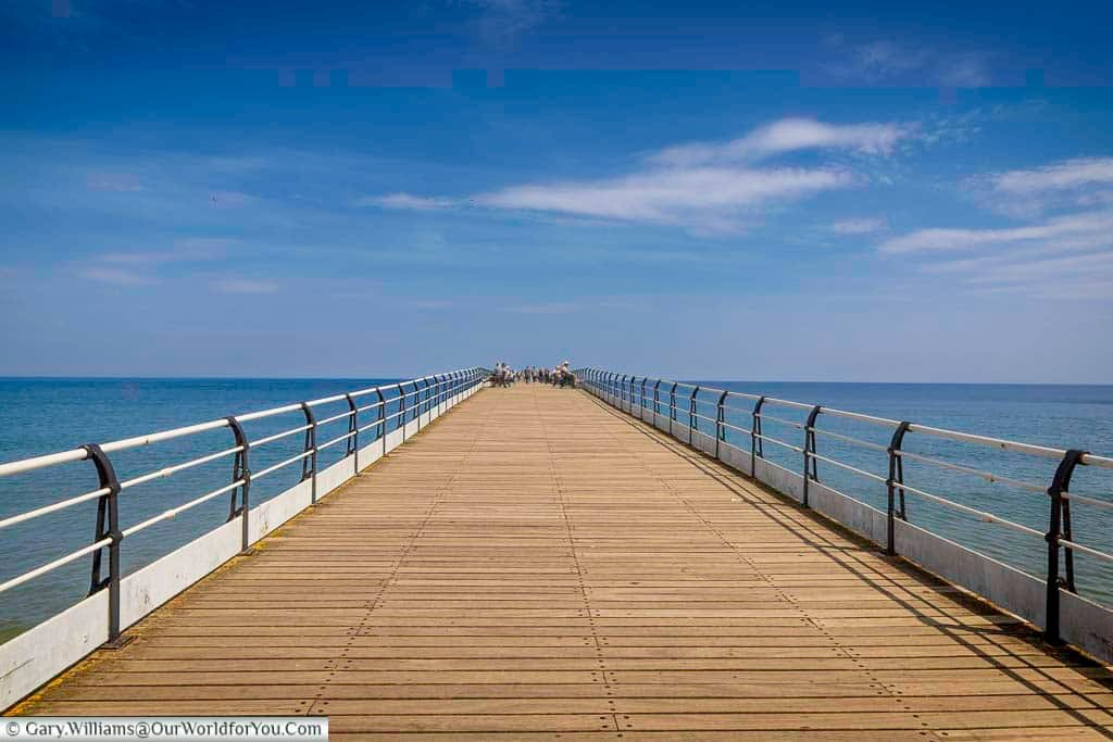 Looking straight down Saltburn Pier, the long wooden boardwalk leads visitors towards the endless blue horizon of the North Sea. This tranquil setting makes it one of the best spots in Yorkshire to soak up the coastal atmosphere.