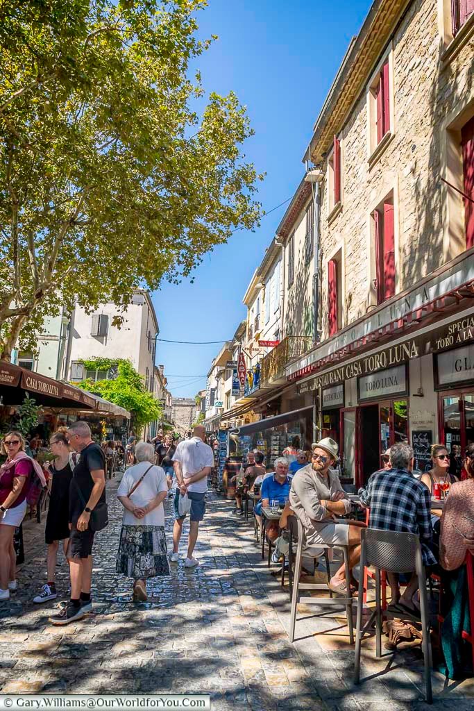 Place Saint Louis in Aigues-Mortes bursts with life as locals and tourists enjoy outdoor cafes under the Provençal sun. Experience the vibrant heart of this historic fortified town in southern France.