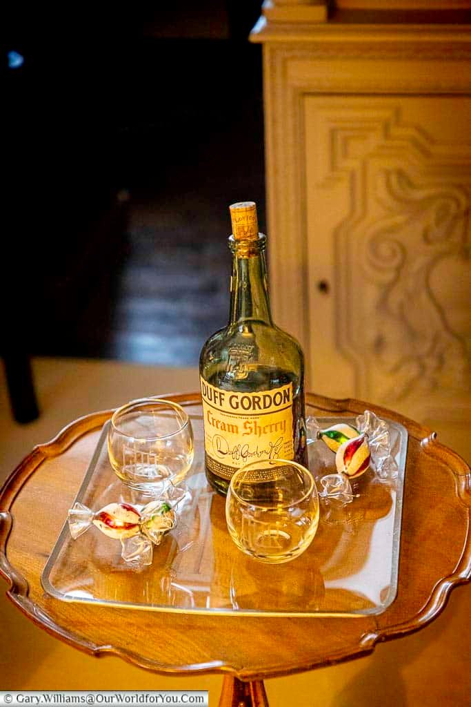 A bottle of Duff Gordon cream sherry and glasses are arranged on a vintage side table at Ightham Mote. The display evokes traditional Christmas hospitality in a historic English country house.