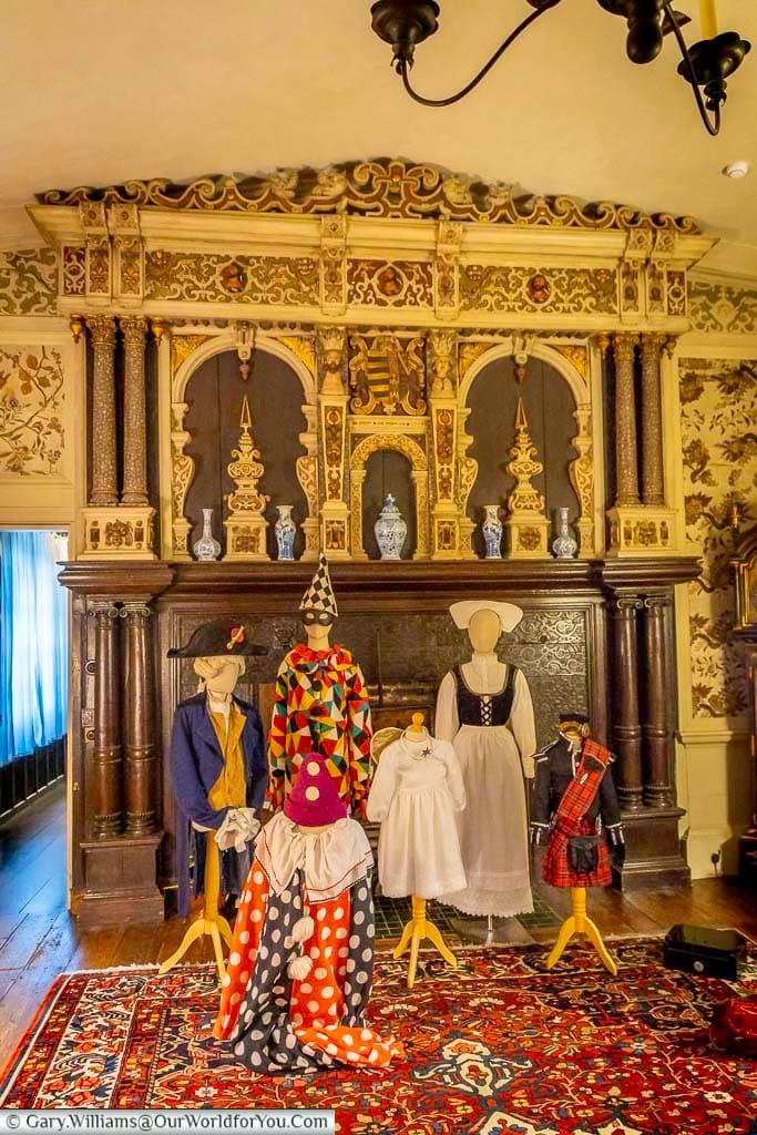 Mannequins dressed in historic costumes are displayed in front of the richly carved fireplace in the Drawing Room at Ightham Mote in Kent. The festive interior highlights the National Trust property’s Tudor heritage and Christmas decorations.