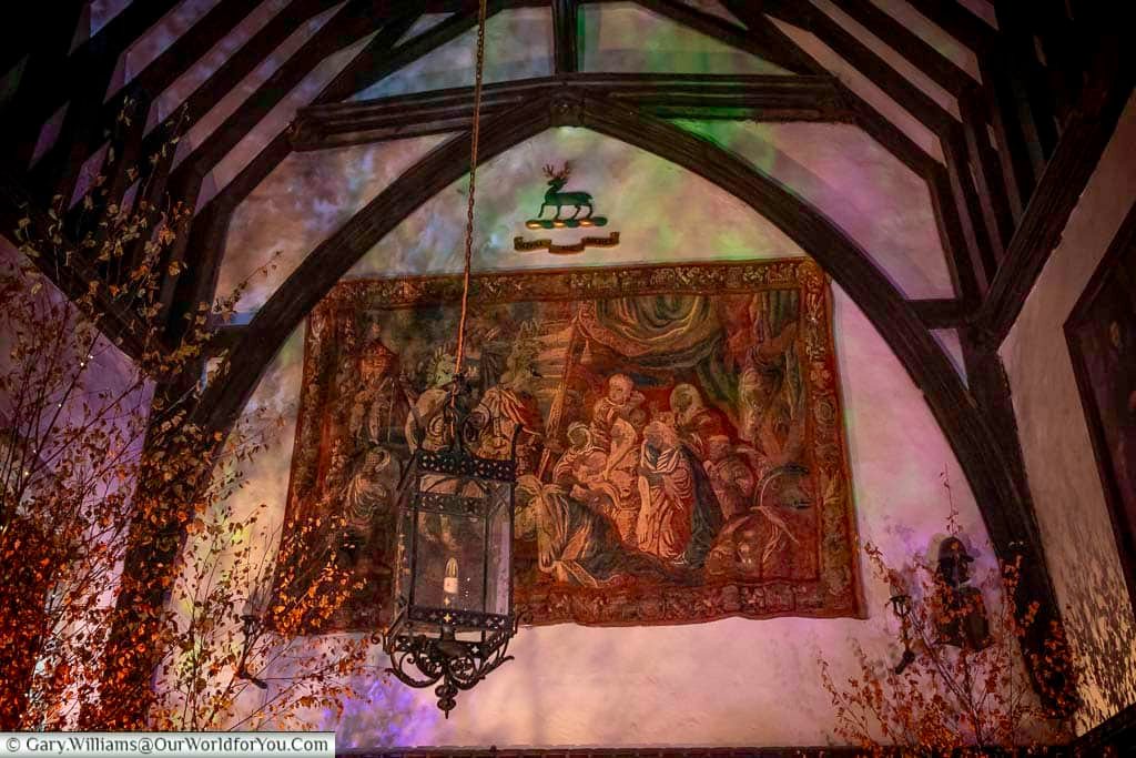 The Great Hall at Ightham Mote is illuminated with coloured lighting, candles and seasonal foliage beneath its timbered roof. This dramatic medieval space reflects the manor’s rich history and festive Christmas displays.