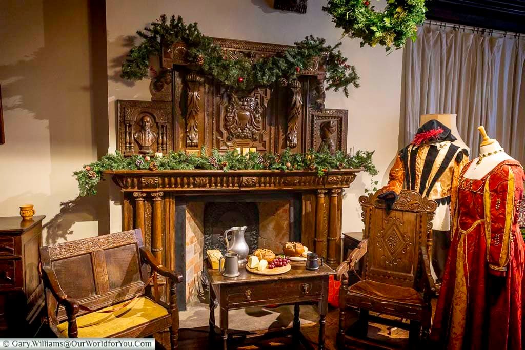 The oriel room at Ightham Mote is dressed for Christmas, featuring a richly carved wooden fireplace adorned with festive greenery and period furnishings. This atmospheric Tudor interior highlights the craftsmanship and seasonal traditions of one of Kent’s finest National Trust properties.