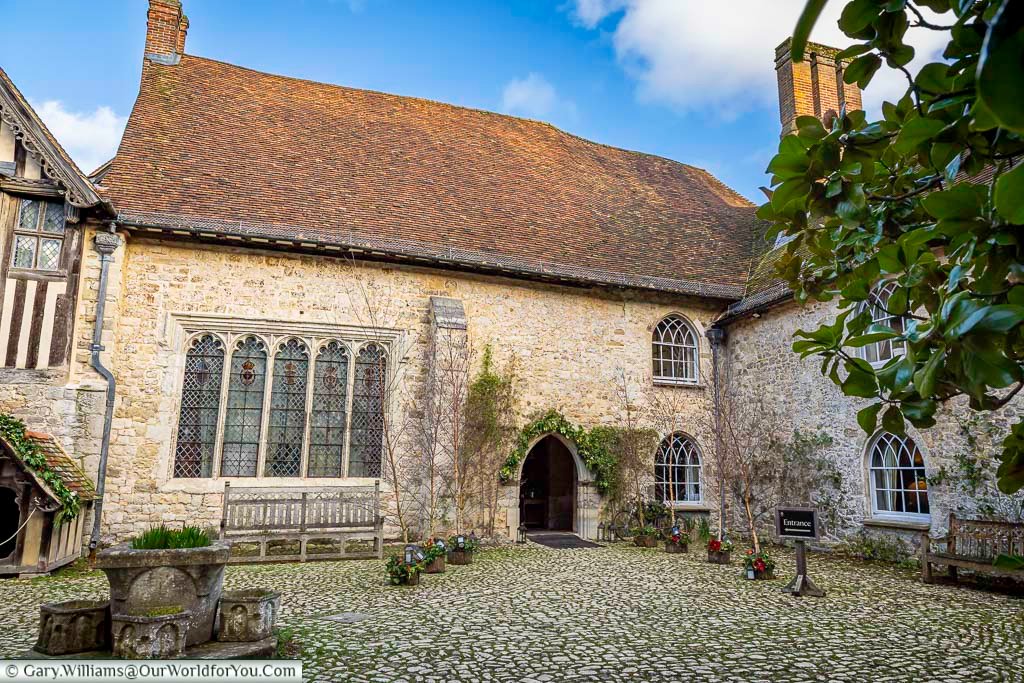 The peaceful inner courtyard of Ightham Mote in Kent, with its stone buildings, arched doorway, and traditional leaded windows surrounding the cobbled ground. This secluded courtyard highlights the manor’s medieval origins and timeless charm within this renowned National Trust property.