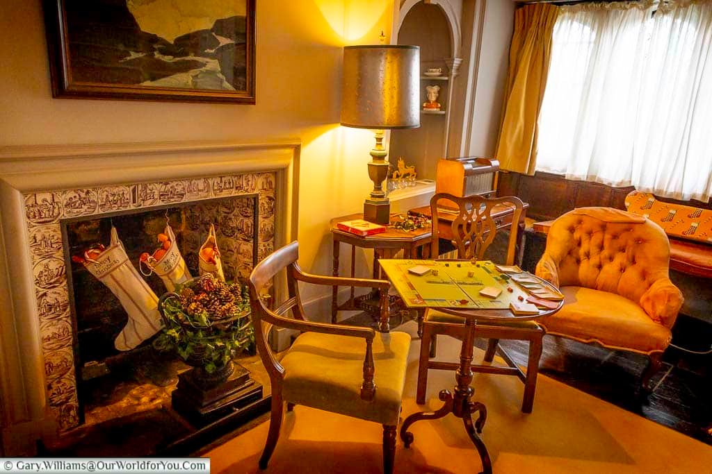 A cosy seating area in the library at Ightham Mote features a decorated fireplace, traditional furniture, and Christmas stockings. This intimate room reflects festive life inside a historic Kent manor.
