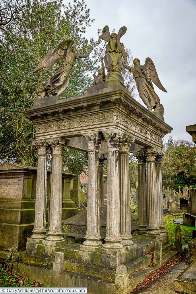 Another tomb at the Kensal Green Cemetery, surrounded by columns with a canopy and four angels on the roof.