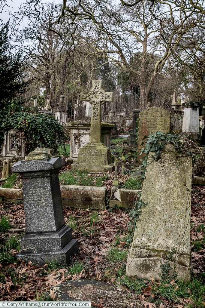 A selection of old gravestones at Kensal Green Cemetery that are all leaning at different angles.
