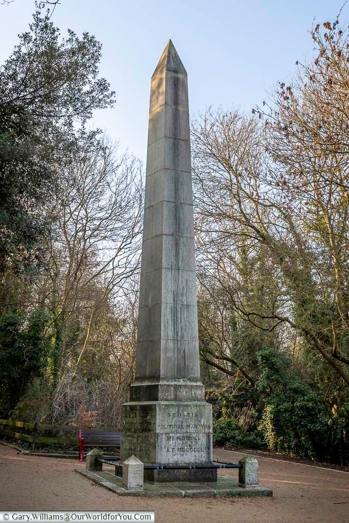 Tall obelisk marking the Scottish Martyrs Memorial in Nunhead Cemetery, south London. This striking monument commemorates political reformers and stands prominently along a tree-lined cemetery path.