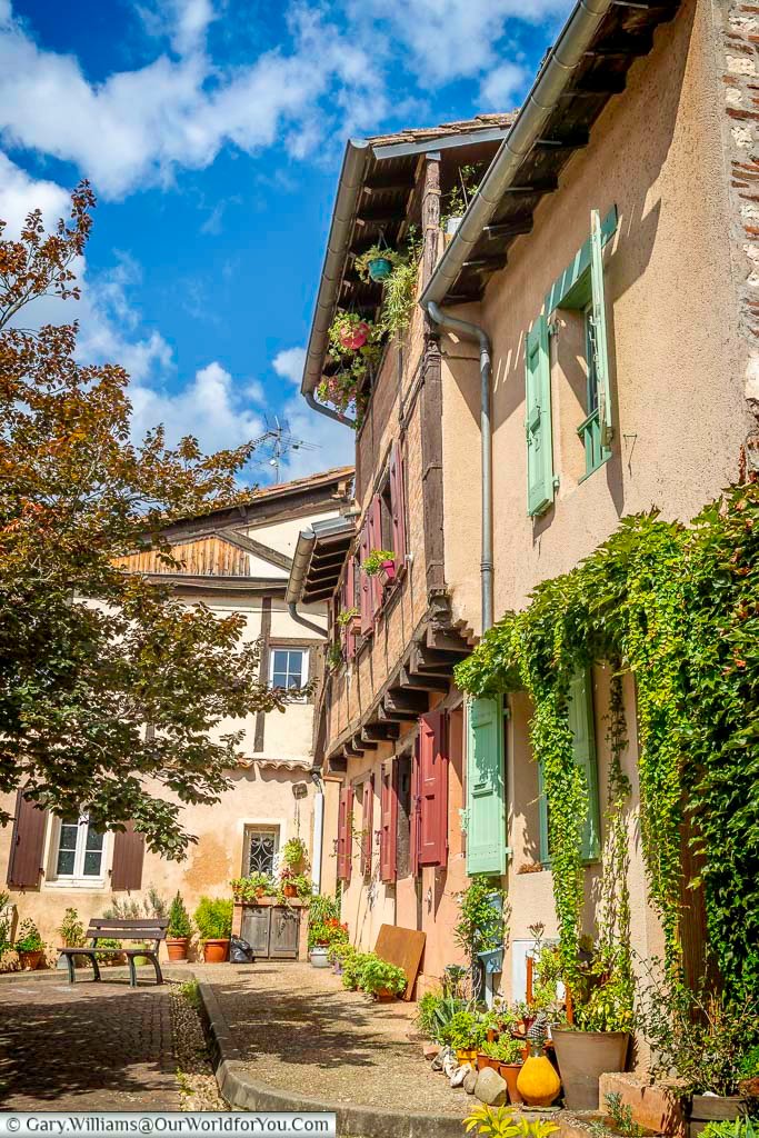 Sunlit residential courtyard in Albi with ivy-covered walls, wooden shutters, and flowering balconies. This tranquil scene highlights the everyday beauty of historic living spaces in southern France.