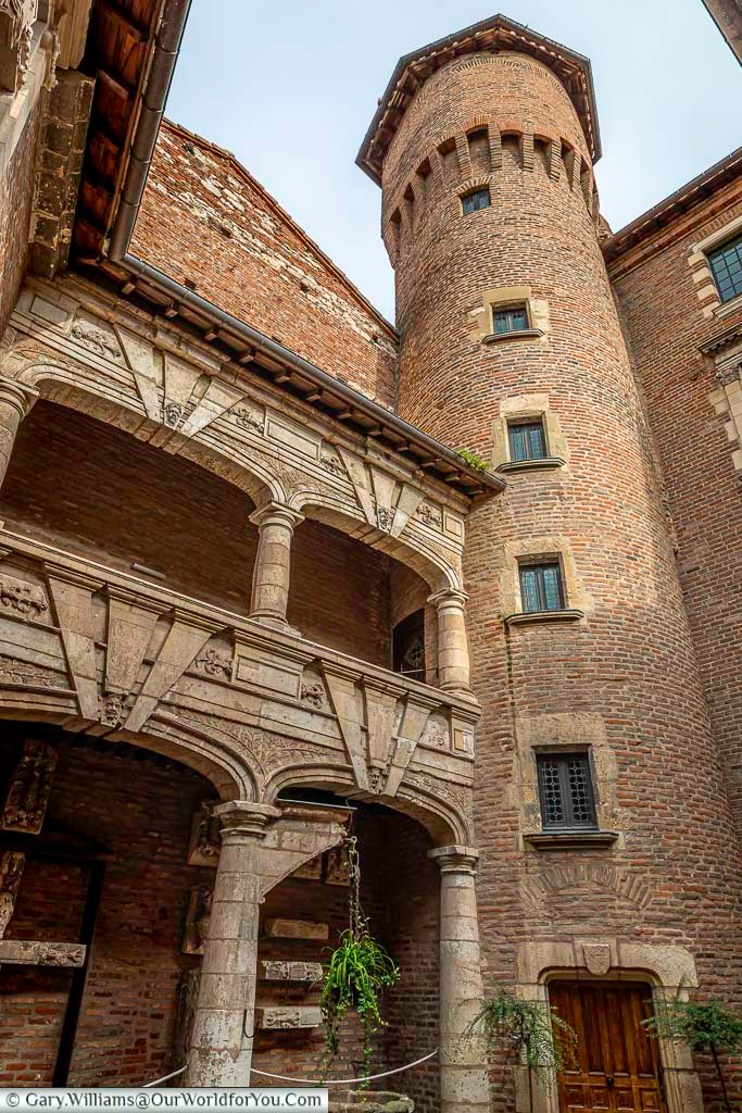 Historic brick courtyard at Hôtel Reynès in Albi, featuring Renaissance stone arches and a cylindrical tower rising above the inner arcade. This elegant courtyard highlights Albi’s architectural heritage and is a hidden gem on an Albi walking tour.