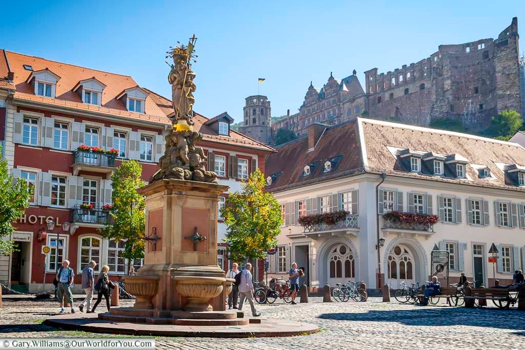 Ornate fountain statue in Heidelberg’s Kornmarkt with pastel townhouses and the ruins of Heidelberg Castle overlooking the square. This picturesque corner blends medieval heritage and everyday life in one of Germany’s most beautiful old towns.