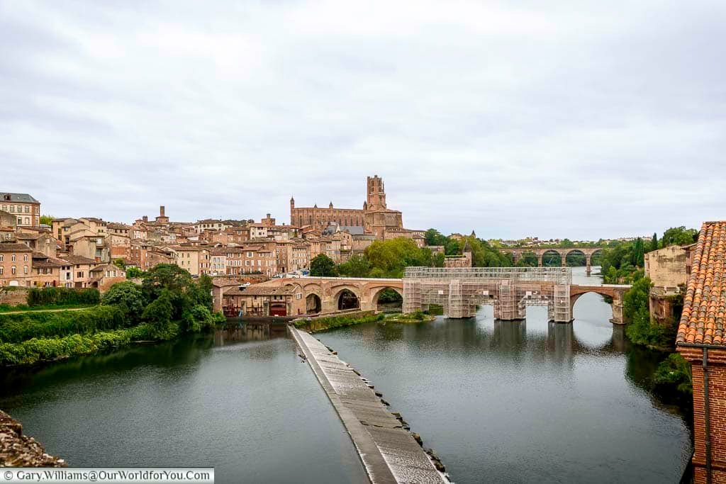 Panoramic view of Albi overlooking the River Tarn with historic bridges and the red-brick skyline dominated by Sainte-Cécile Cathedral. This scenic riverside view highlights why Albi is one of the most beautiful cities to visit in Occitanie, France.