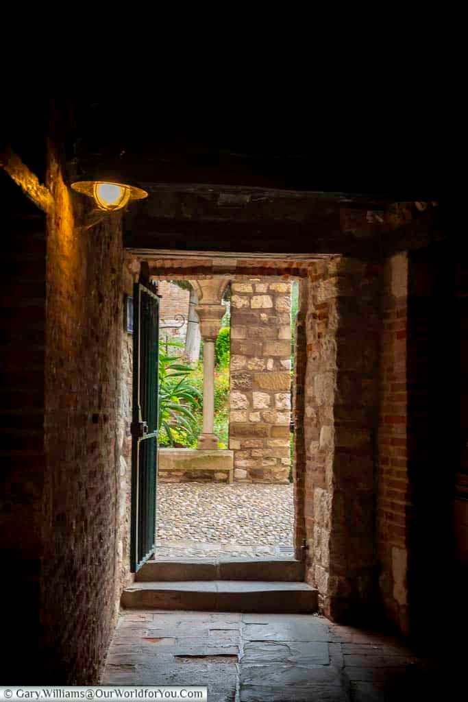 Narrow stone passageway leading into the Saint-Salvi Cloister in Albi, lit by a single lamp and framed by medieval brickwork. These secret alleys reveal the atmospheric side of historic Albi and are perfect for exploring on foot.