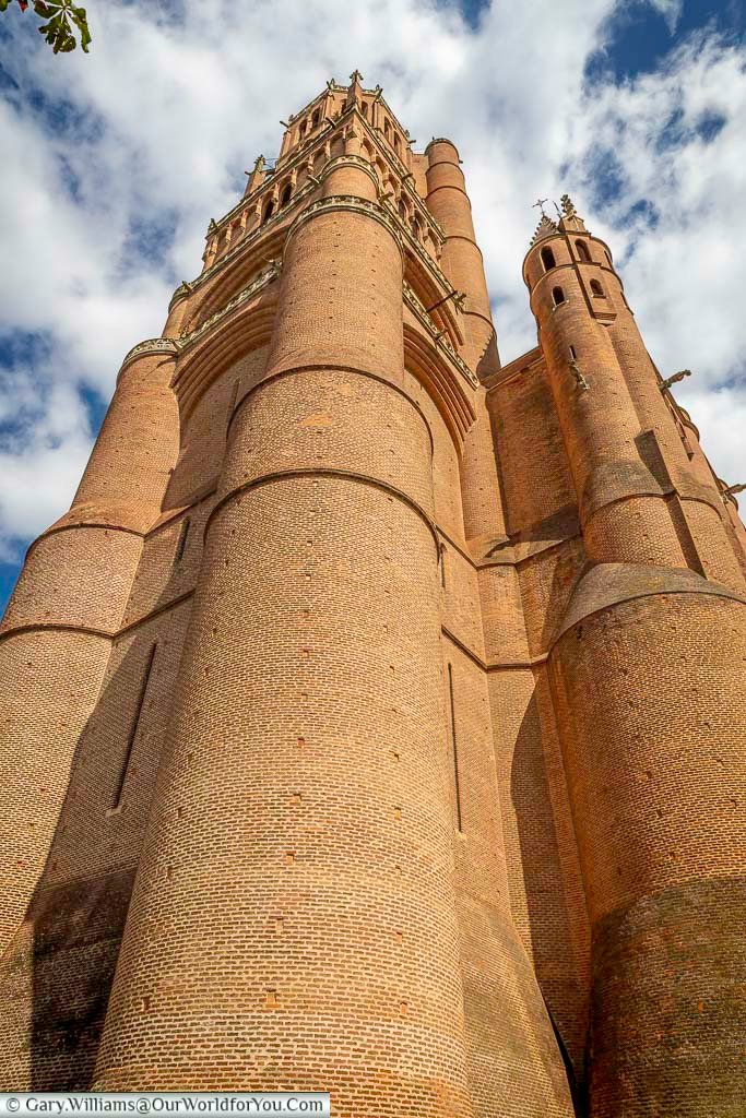 Low-angle view of the towering brick bell tower of Albi Cathedral, showcasing its powerful Gothic architecture against a dramatic sky. The distinctive red-brick structure is one of Albi’s most iconic landmarks and a highlight of any visit to southern France.