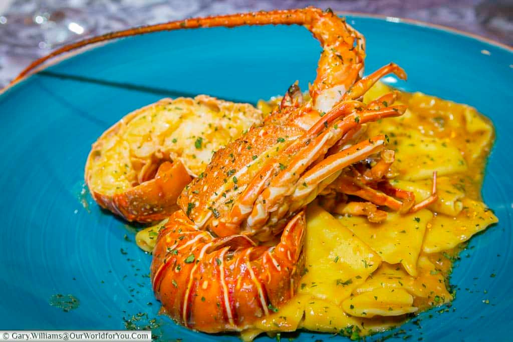 A large langoustine on a bed of Ravioli on a blue plate at the Restaurant "Bon Appetit"