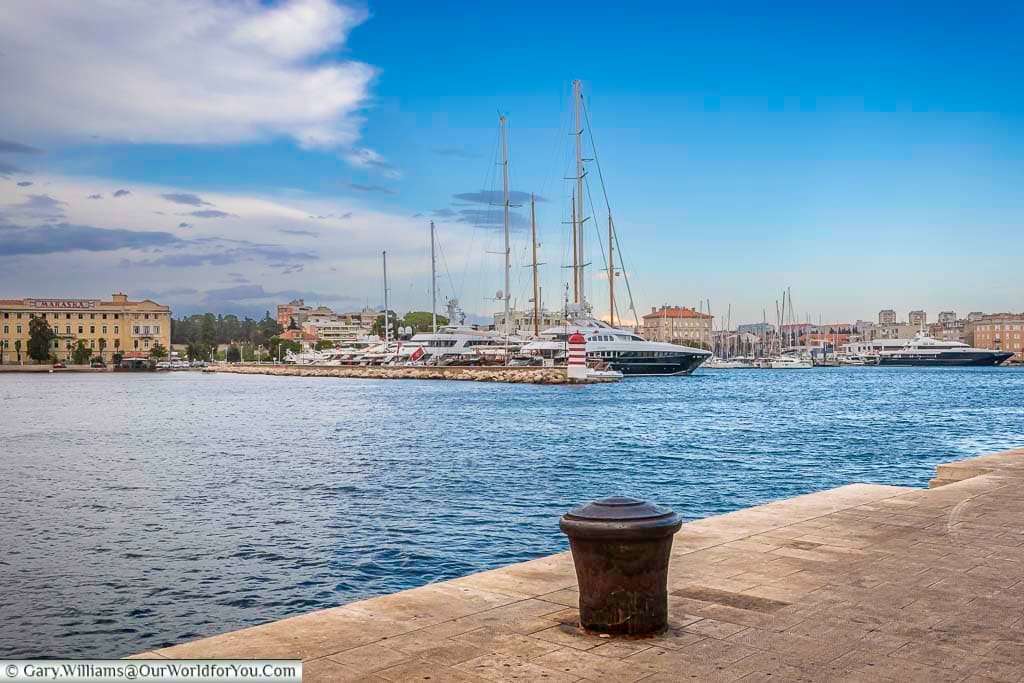 Standing on the marina side, with expensive, superyachts and tall sailing ships moored up, overlooking the ancient city of Zadar, Croatia