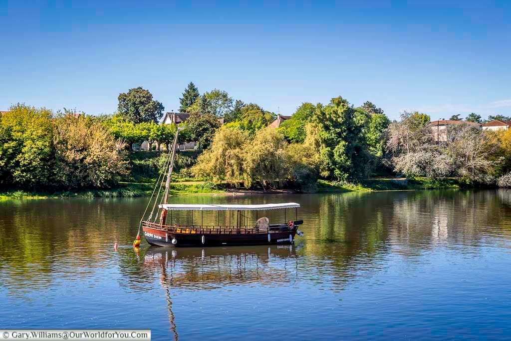 A traditional gabarre boat rests on the calm waters of the Dordogne River in Bergerac, reflecting the region’s historic river trade. These boats now offer scenic cruises and are an iconic symbol of Dordogne heritage.