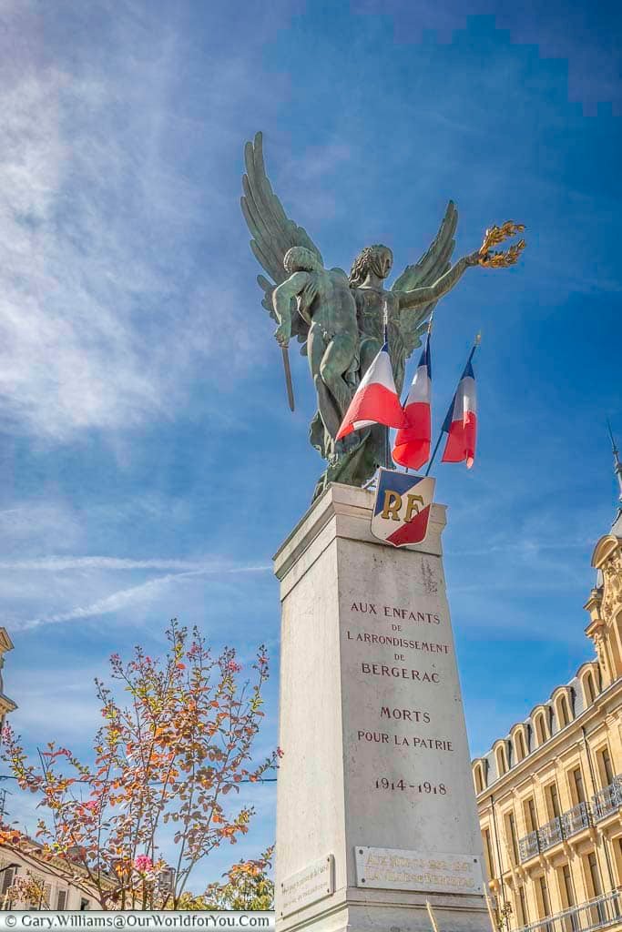 The First and Second World War memorial in Bergerac features a winged bronze figure atop a stone column in a central town square. French flags and engraved inscriptions honour the local men and women who lost their lives during both conflicts.