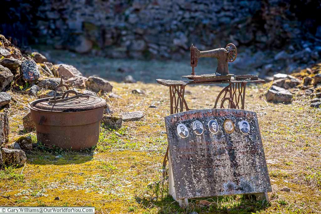 A personal family memorial in Oradour-sur-Glane featuring a sewing machine and photographs, symbolising the lives lost during the massacre. This poignant tribute highlights the everyday people whose stories are remembered in the preserved ruins of the village.