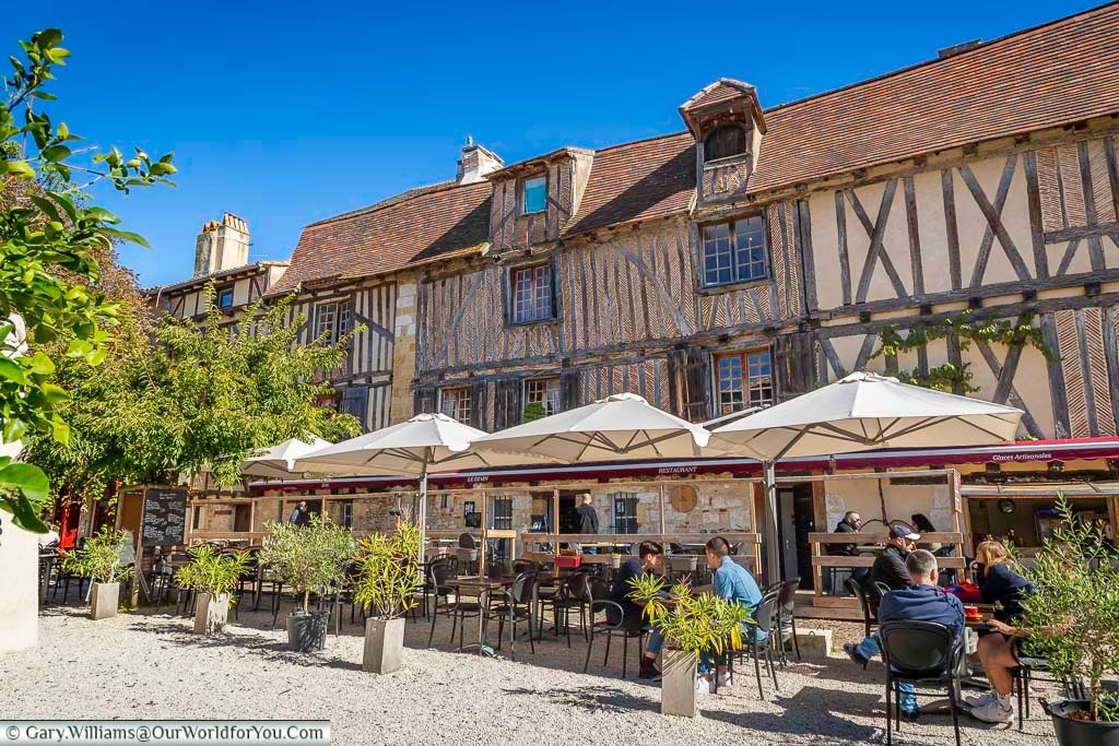 Outdoor cafés line the medieval half-timbered buildings of Place de la Mirpe in Bergerac, creating a relaxed and welcoming atmosphere. This scenic square is a must-see stop on a walking tour of Bergerac in the Dordogne region of France.
