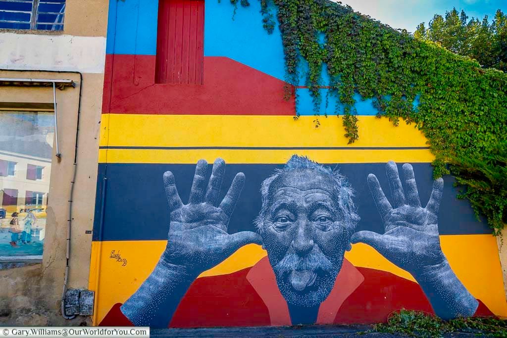 A bold and playful mural by street artist Ladybug shows a man pulling a funny face against a bright striped background in Bergerac, France. This eye-catching artwork is part of the town’s growing street art scene in the Dordogne.