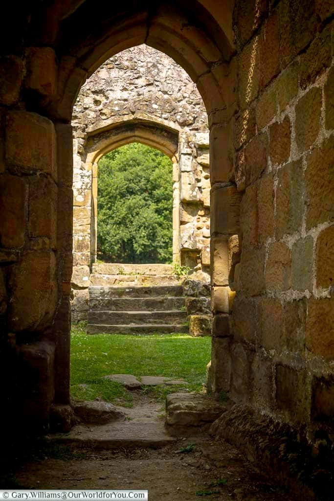 A dramatic stone archway leading through the medieval ruins of Mount Grace Priory, framing another doorway and woodland beyond. This atmospheric view captures the timeless beauty of one of North Yorkshire’s most historic monastic sites.