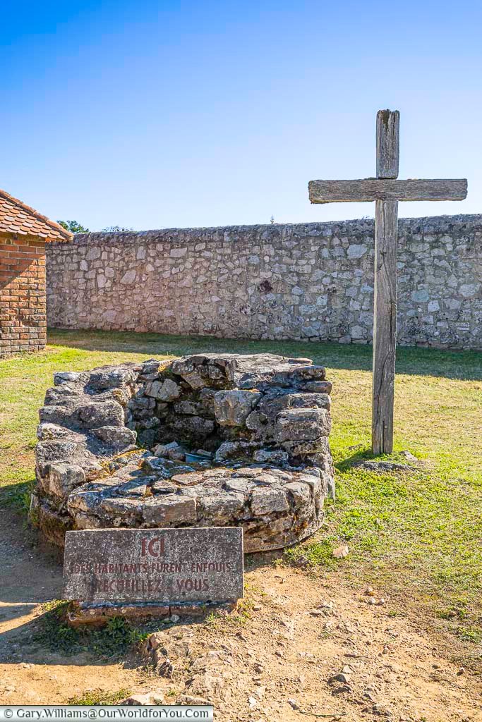 A stone well and wooden cross stand in the ruins of Oradour-sur-Glane, marking one of the village’s most haunting sites. This tragic location reflects the devastation and loss suffered during the 1944 massacre in occupied France.