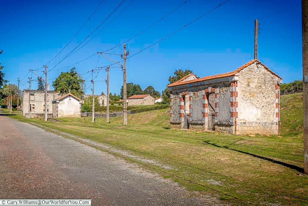 The abandoned tram station ruins in Oradour-sur-Glane, with old railway infrastructure and tracks still visible in the grass. This historic site is part of the preserved village left untouched as a memorial to the WWII massacre.