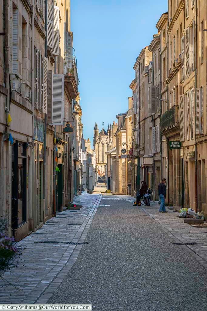 A charming cobbled street lined with historic buildings leads toward a church in the old town of Poitiers, France. The atmospheric lane captures the character of this beautiful medieval city and its well-preserved historic centre.