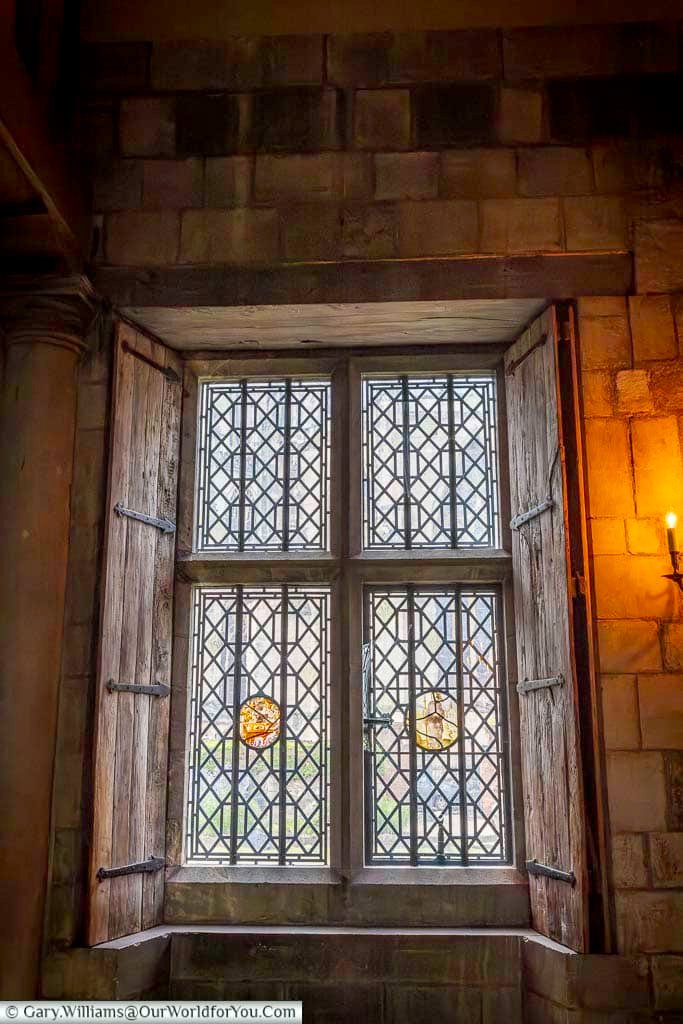 Lead-framed lattice windows with wooden shutters illuminate the Great Hall at the Treasurer’s House in York. These historic architectural details showcase the craftsmanship found in this beautifully preserved medieval townhouse.