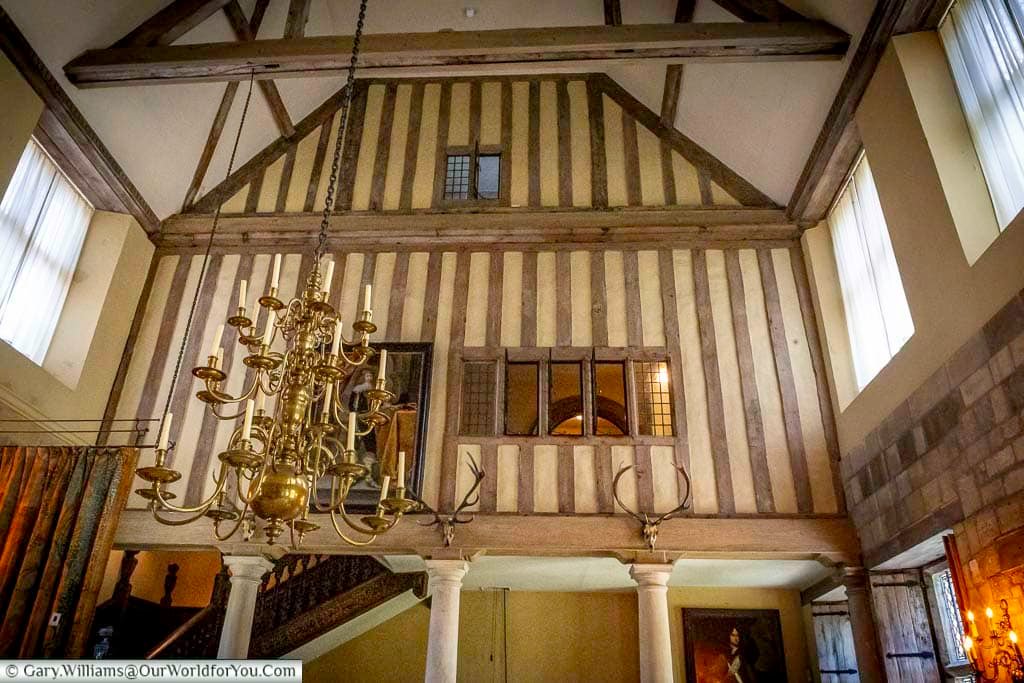 A timber-framed hall with exposed beams and a grand chandelier showcases medieval architectural features inside the Treasurer’s House in York. This atmospheric interior blends historic charm with centuries of York’s rich heritage.