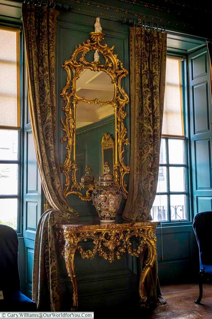 An ornate gilded mirror and decorative console table adorn a richly panelled room inside the Treasurer’s House in York. The luxurious detailing reflects the elegant period interiors preserved within this historic York attraction.