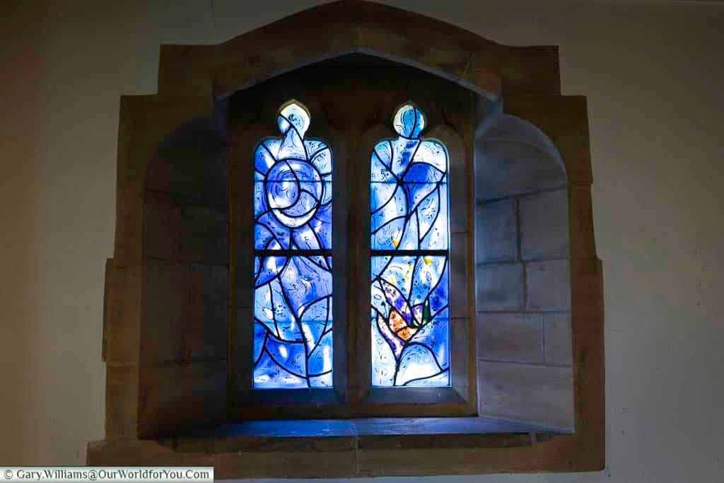 A deep blue Marc Chagall stained glass window in All Saints’ Church, Tudeley, features abstract figures and a crescent moon motif. The rich colours and symbolic design make this a standout highlight among Kent’s hidden artistic gems.