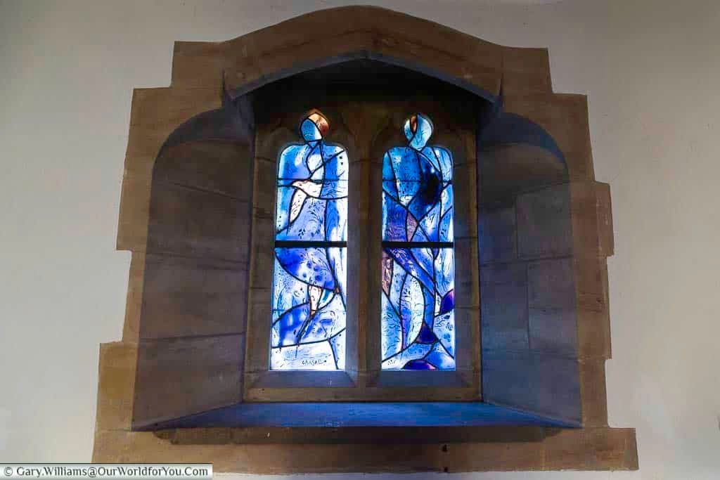 This Marc Chagall stained glass window in Tudeley Church displays flowing blue tones with a delicate white bird motif. The expressive composition enhances the peaceful and contemplative atmosphere of this historic Kent church.